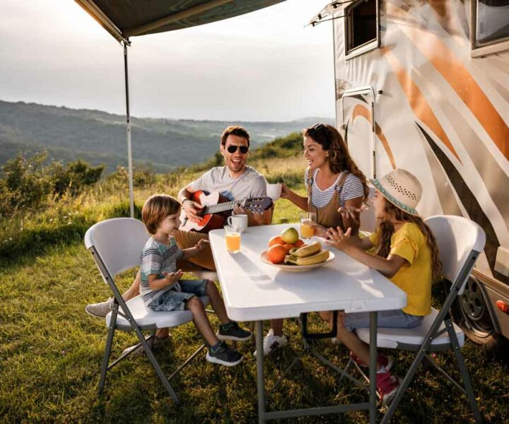 Famille qui prend son déjeuné devant le camping-car qu'ils ont loué